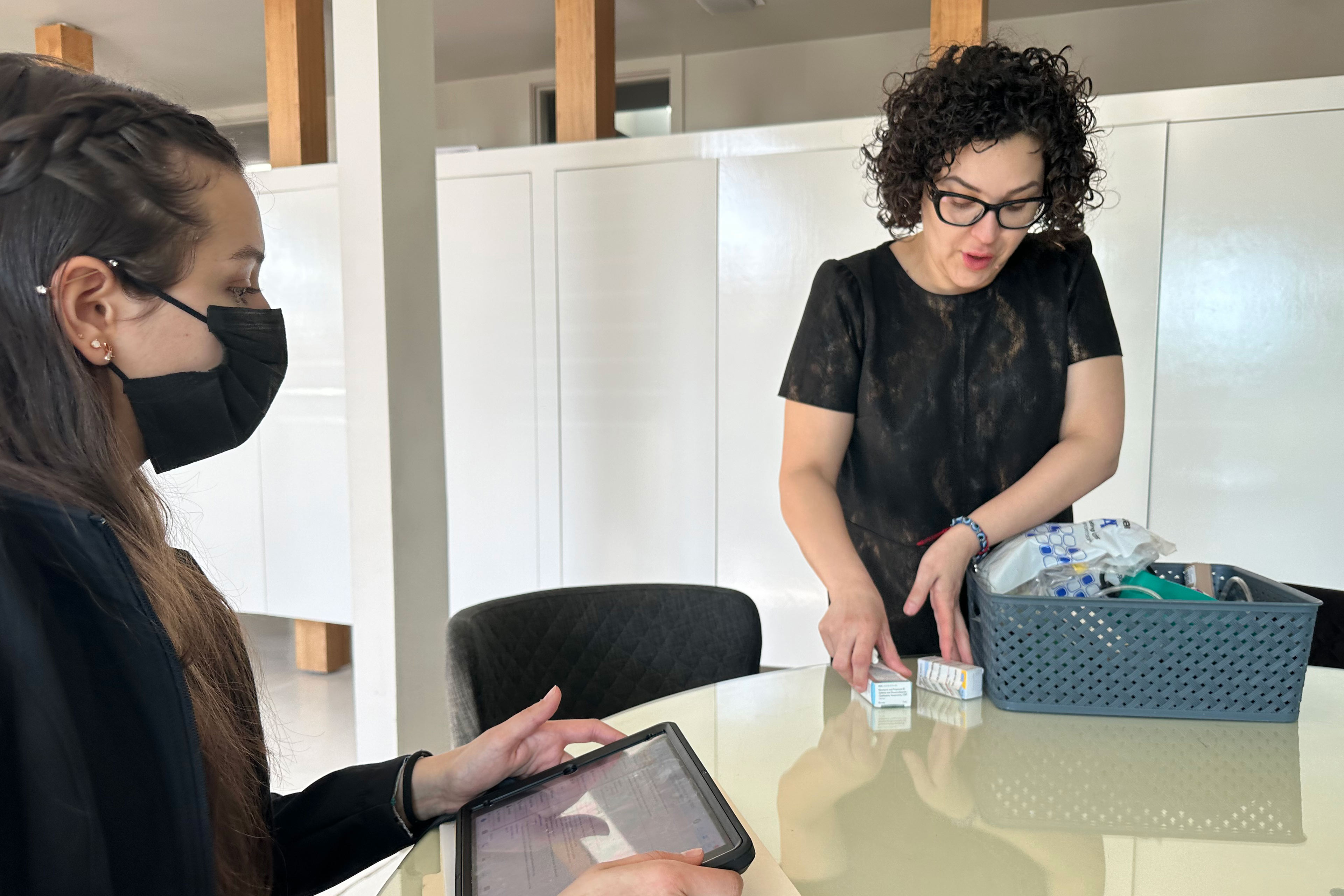 A photo of a mother showing a community health worker her son's medications.