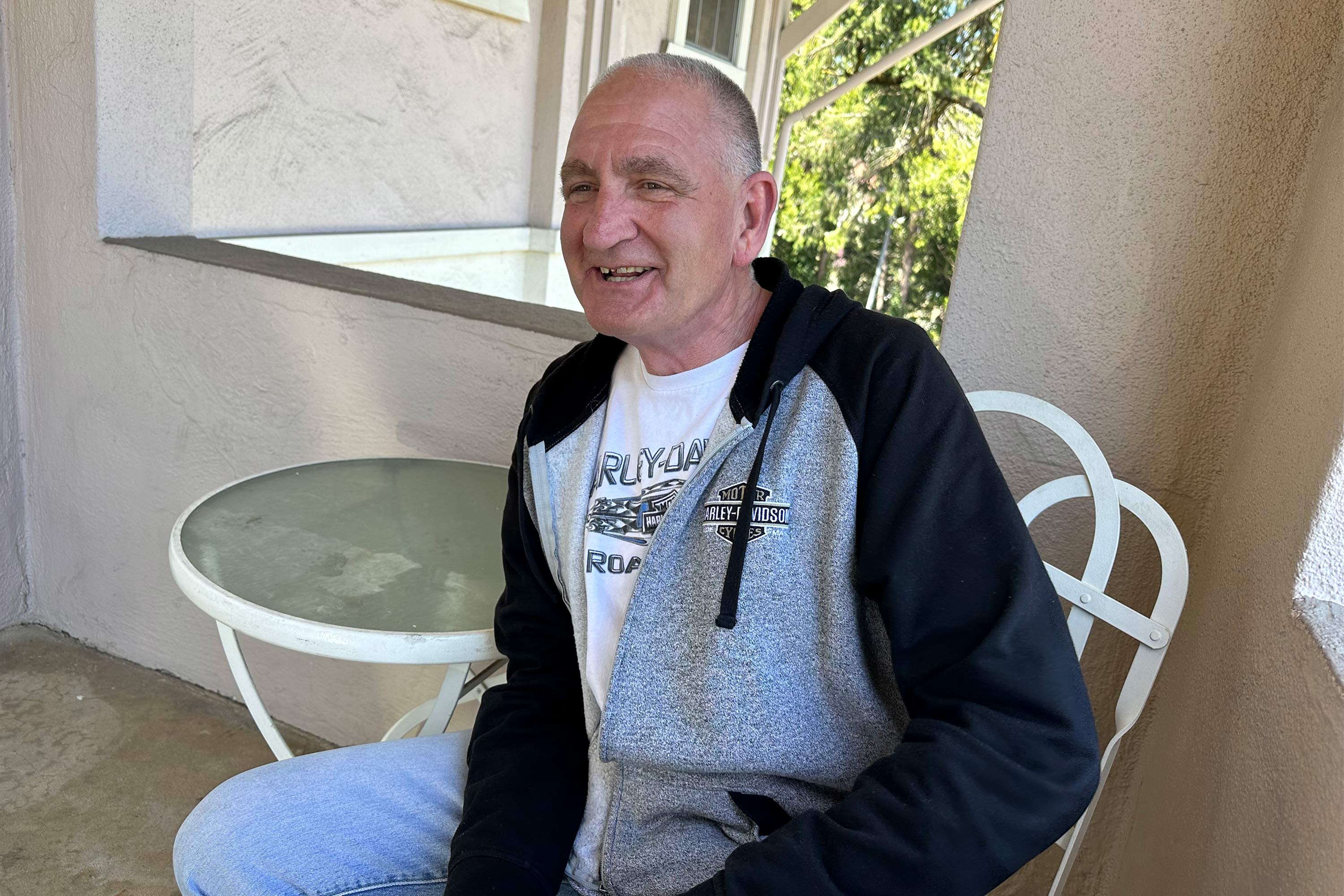 A photo of a man smiling while sitting at a table.