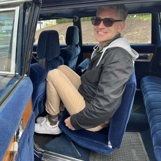 A photo of a person sat in the jump seat inside a Volvo limo. 