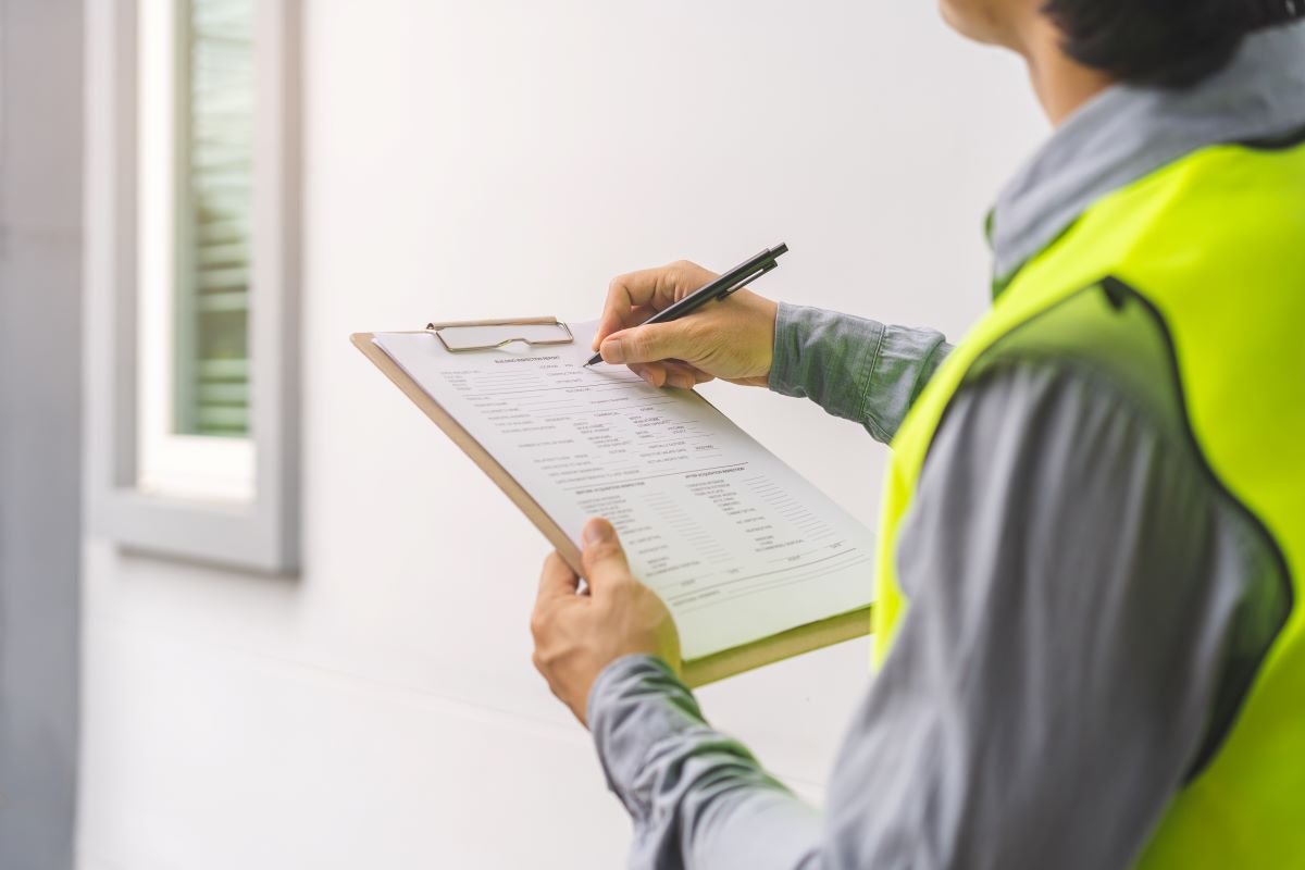 Home surveyor with clipboard checking house