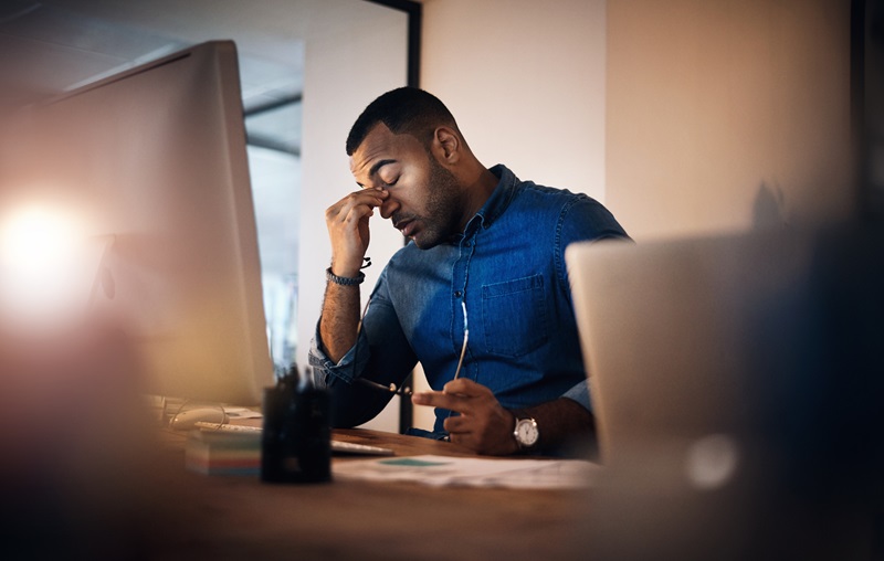 Shot of a young businessman looking stressed out while working in an office at night