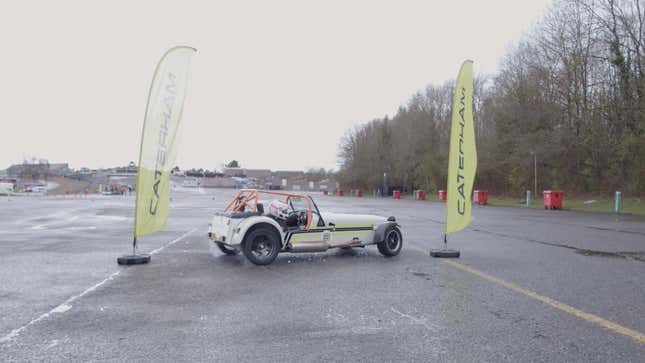 A photo of a person drifting between two Caterham flags. 
