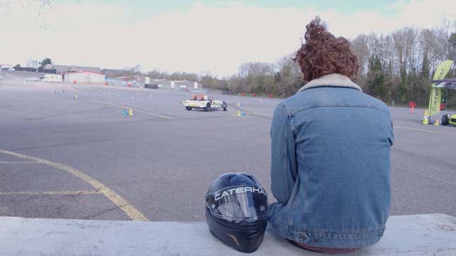 A photo of a person sat on a wall with a helmet next to them. 