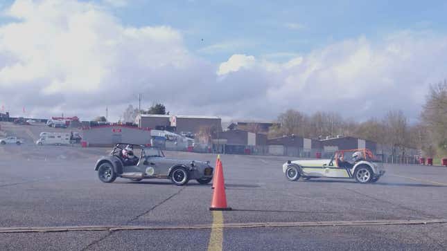 A photo of two Caterham cars drifting on a track. 