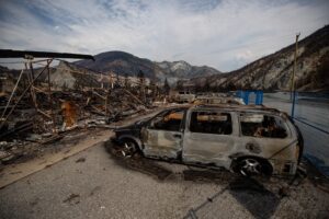 The remains of a large structure and vehicles destroyed by the 2021 Lytton Creek wildfire.