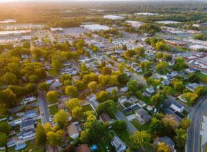 Incredible view from a height to a small town in houses and shopping mall of parking lot space at sunset