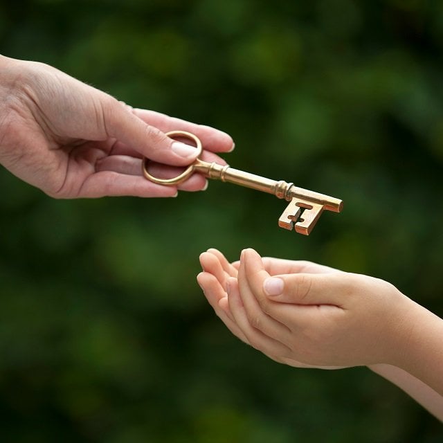 Hand passing off key to outstretched hands of child