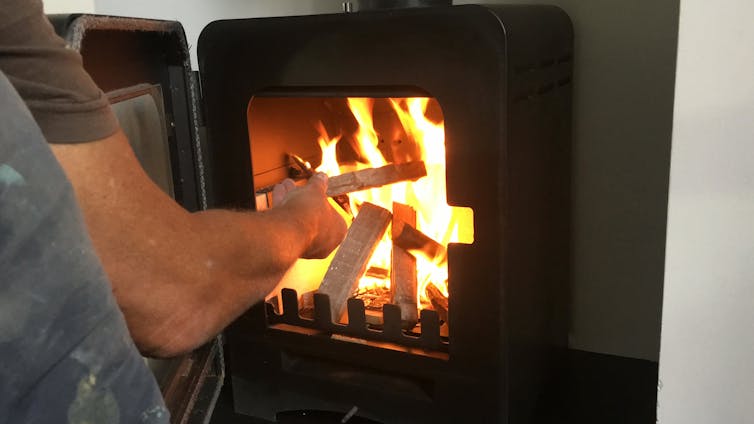 A person puts wood in a wood heater