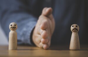 Palm hand blocking and divide between Man and woman wooden figure for resolving conflict and mediate management concept.