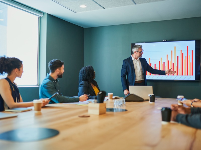 Diverse business team sitting around a conference table having a meeting and discussing financial data.