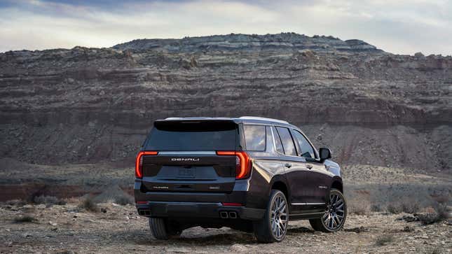 the rear of a GMC Yukon Denali parked in front of a rock formation 