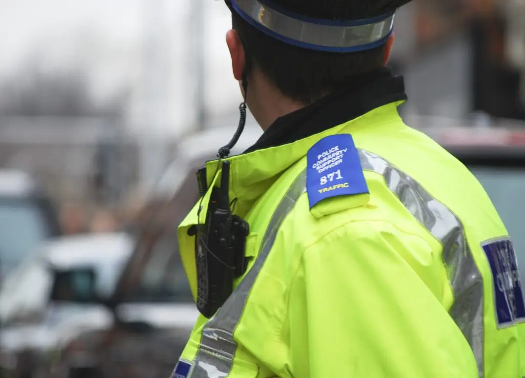 Police community support officer looking at parked cars