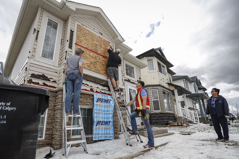 Boarding up a house as residents clean up after June 2020 hailstorm in Calgary.