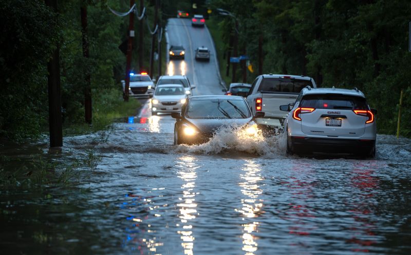 Cars drive slowly through flooded streets in Sainte-Anne-de-Bellevue on the Island of Montreal after heavy rains hit the area on Friday, August 9, 2024. THE CANADIAN PRESS/Peter McCabe