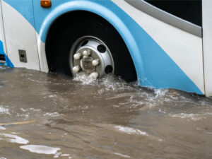 Bus splashing through a large puddle on a flooded street