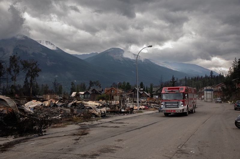 A fire truck travels past a devastated residential block in Jasper, Alta., on Friday July 26, 2024. Jasper residents who lost their homes in last month’s wildfires face unique rebuilding challenges tied to leasing provisions nearly as old as Canada is, followed by two sets of modern rules dictating what they can and can’t construct. THE CANADIAN PRESS/Amber Bracken