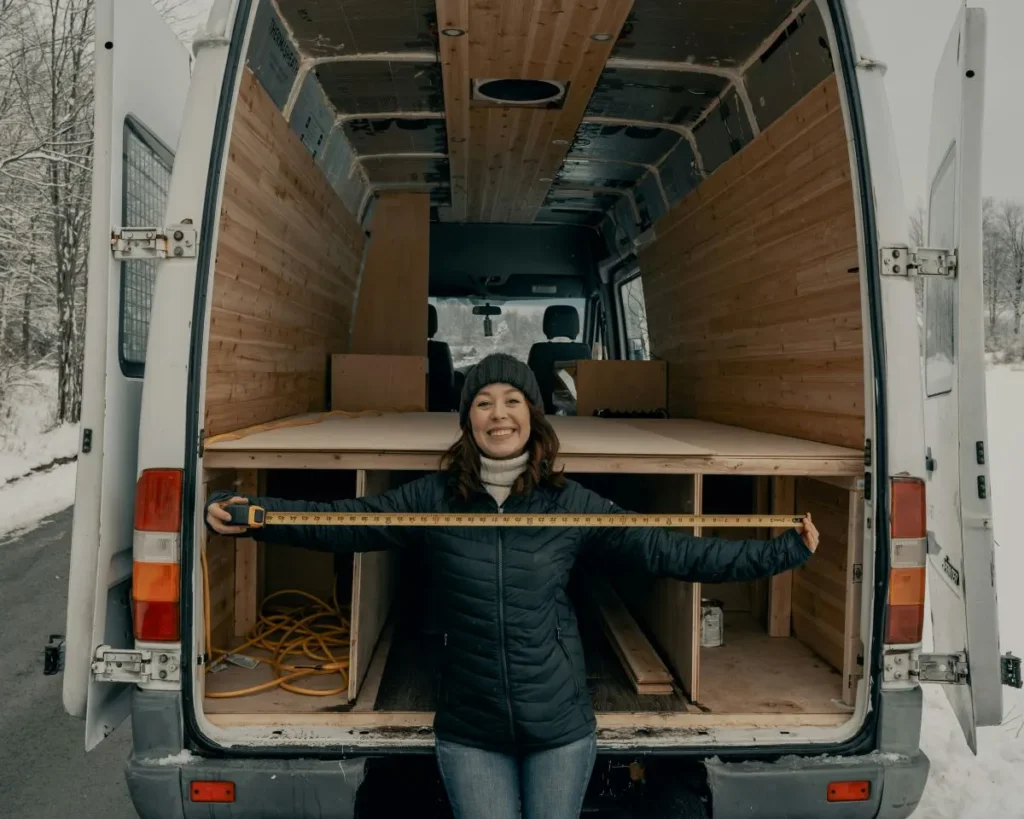 Woman measuring van with the back of the van on show behind her