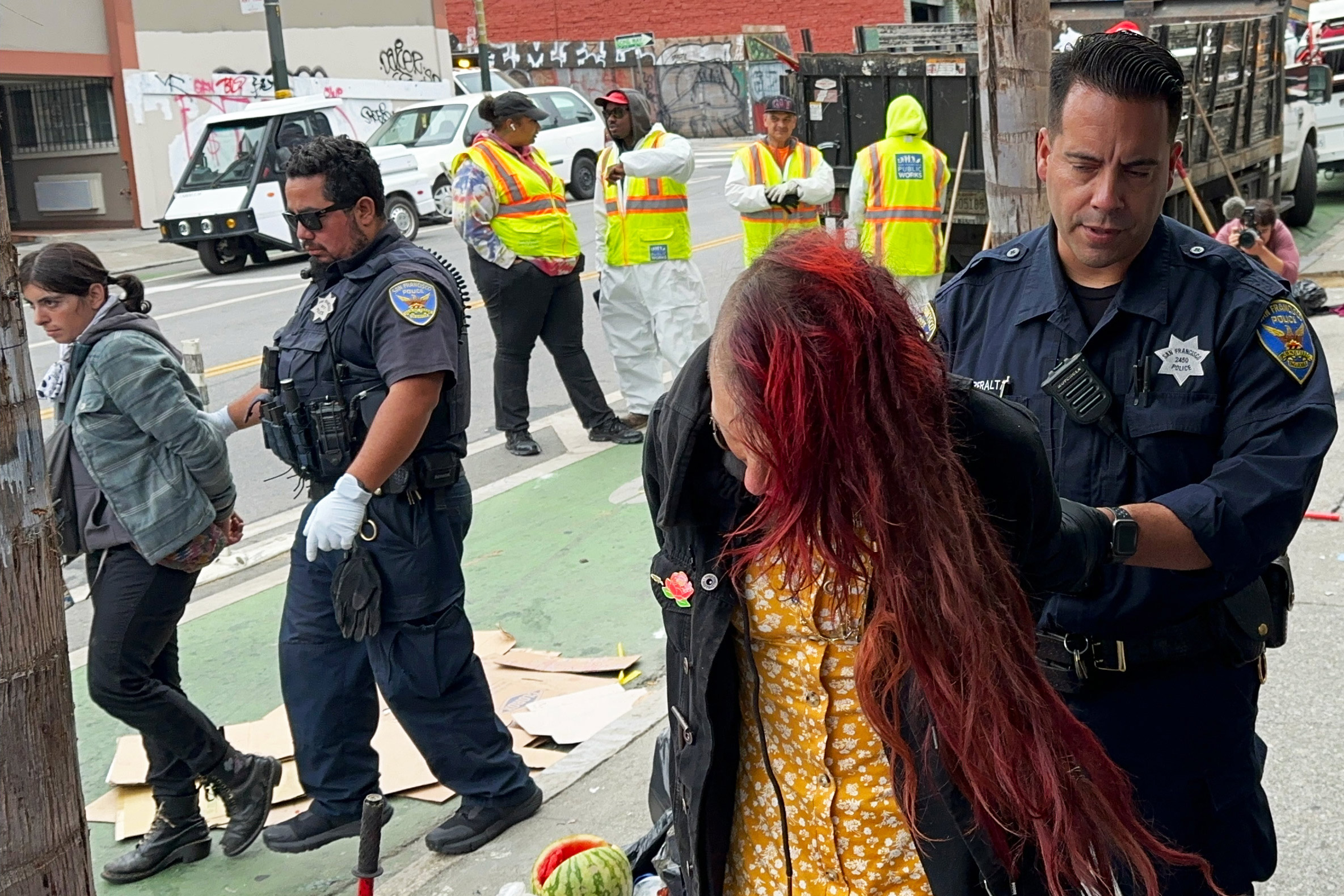 A photo of two homeless people being handcuffed.