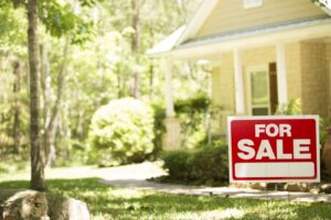 Home for sale with real estate sign in spring or summer season.