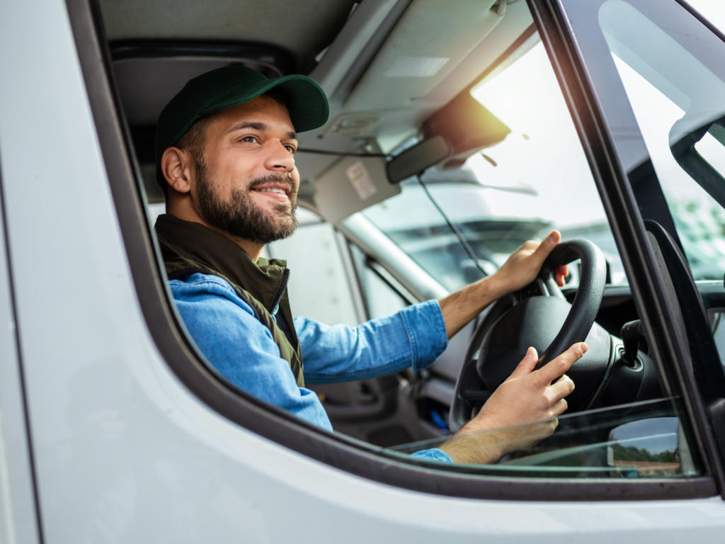 Young man wearing cap and smiling while driving his work van