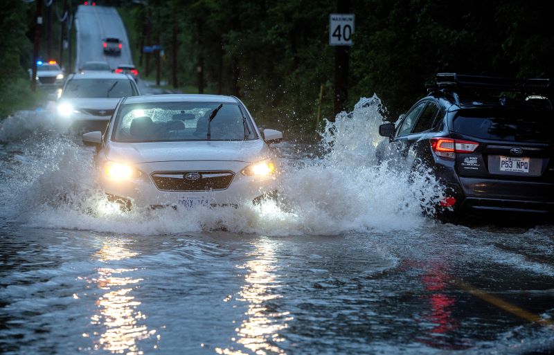 Cars drive slowly through flooded streets in Sainte-Anne-de-Bellevue on the island of Montreal after heavy rains hit the area on Friday, August 9, 2024. THE CANADIAN PRESS/Peter McCabe