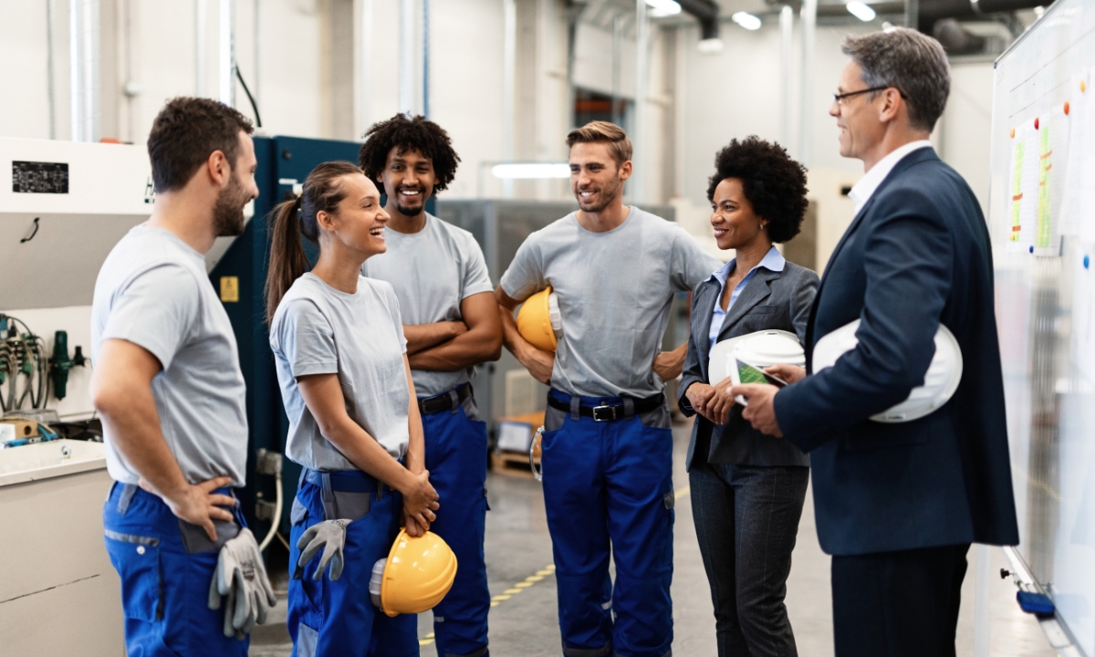 a group of workers all standing and smiling together and holding hard hats