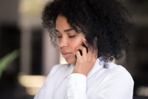 Close up of pensive millennial African American woman talk on smartphone thinking of idea or news, serious black female speak over cell, lost in thoughts considering something. Technology concept